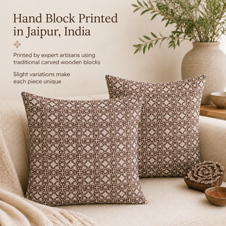 Two square throw pillows with a brown and beige carved wooden block pattern are styled on a light beige sofa in a cozy living room setting, with a ceramic vase of greenery in the background. Text on the left reads 'Hand Block Printed in Jaipur, India' with descriptive copy.