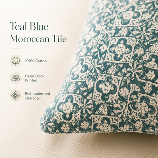 A close-up of a decorative throw pillow with a teal blue and cream Moroccan tile block-print pattern, shown next to text highlighting its features: 100% cotton, hand block printed, and rich patterned character.