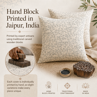 Two decorative throw pillows with a delicate floral block-print pattern in dark brown on a warm cream fabric, styled on a beige textured rug with a wooden stamp and ink bowl. Text overlays highlight the handcrafted block printing in Jaipur, India.
