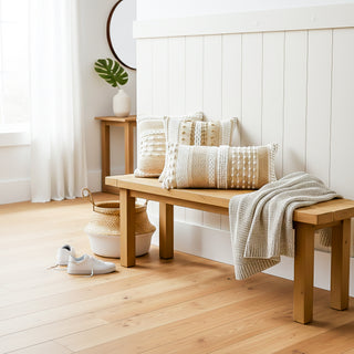 Wooden bench with pillows and a blanket in a bright room