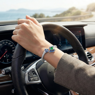 Hand on steering wheel with a decorative bracelet, driving a car with scenic background