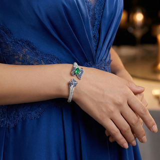 Close-up of a person wearing a blue dress and a silver bracelet with green gemstone.