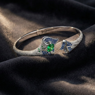 Silver bracelet with green and blue gemstones on a dark fabric background