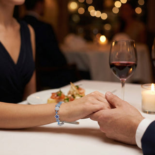Two people holding hands at a romantic dinner with a glass of wine and candlelight.