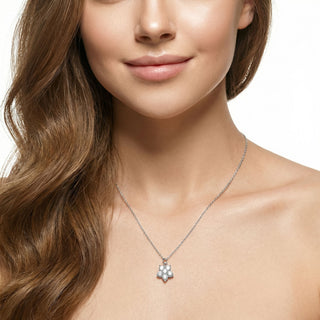 Close-up of a woman wearing a silver necklace with a floral pendant on a white background