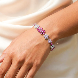 Bracelet with pink and purple gemstones on a wrist against a neutral background