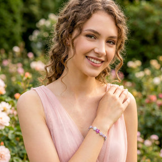 Woman in a pink dress with a floral bracelet, standing in a garden.
