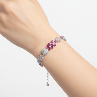 Bracelet with floral design and pink gemstones on a wrist against a white background