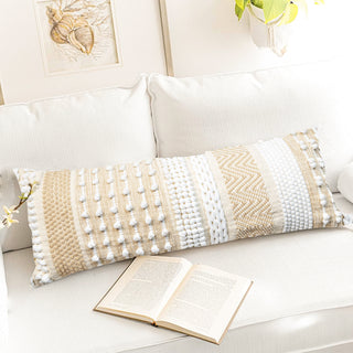 Decorative pillow with geometric pattern on a white sofa next to an open book