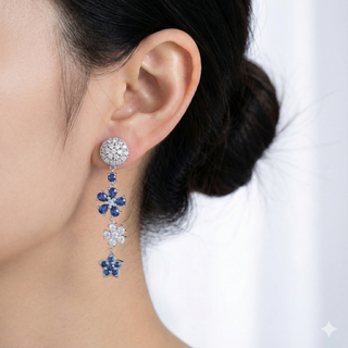 Close-up of a person wearing a pair of earrings with blue and clear gemstones.