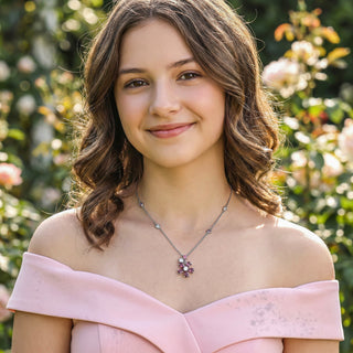 Woman wearing a pink off-shoulder top with a necklace in a garden setting