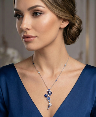 Woman wearing a blue dress with a necklace featuring blue stones.