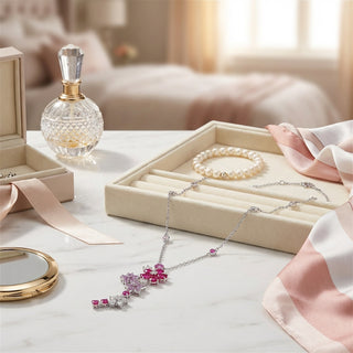 Jewelry set with necklace, bracelet, and perfume bottle on a table.